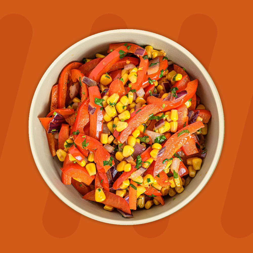 A bowl of vibrant sautéed vegetables featuring red bell peppers, sweet corn, and diced red onions, garnished with fresh chopped parsley, set against a warm orange background.